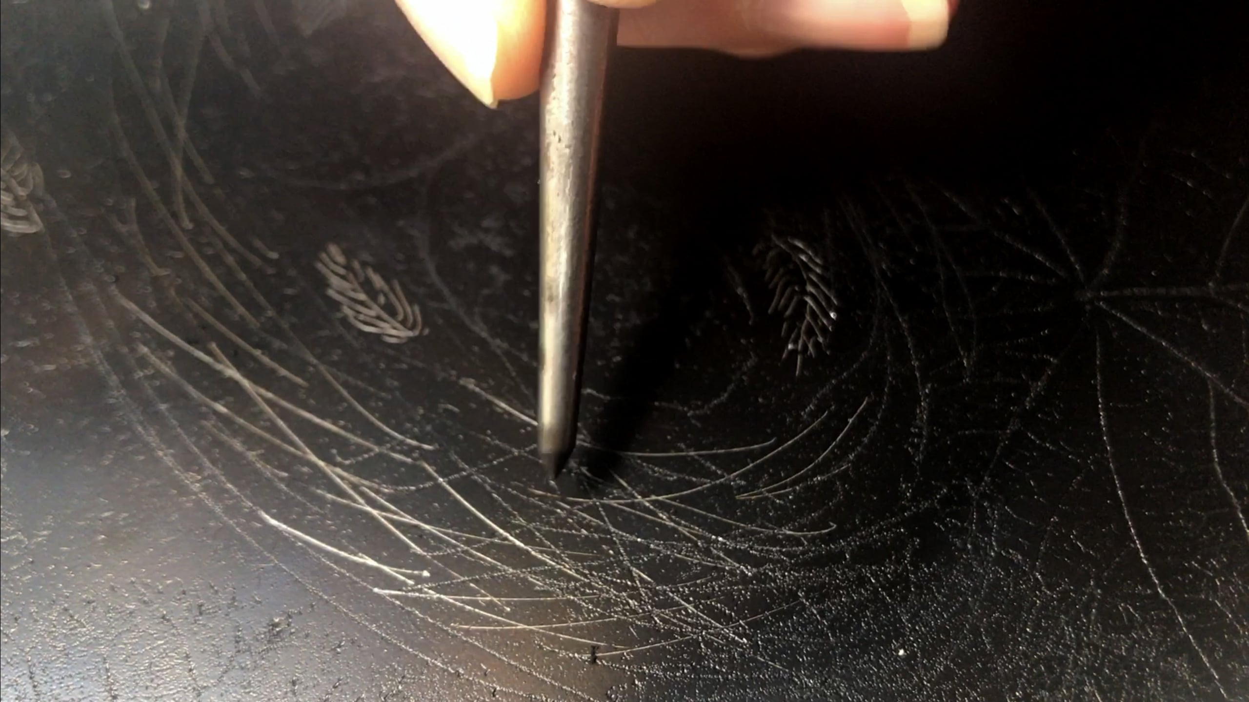 An etching being completed by a person engraving the stencil