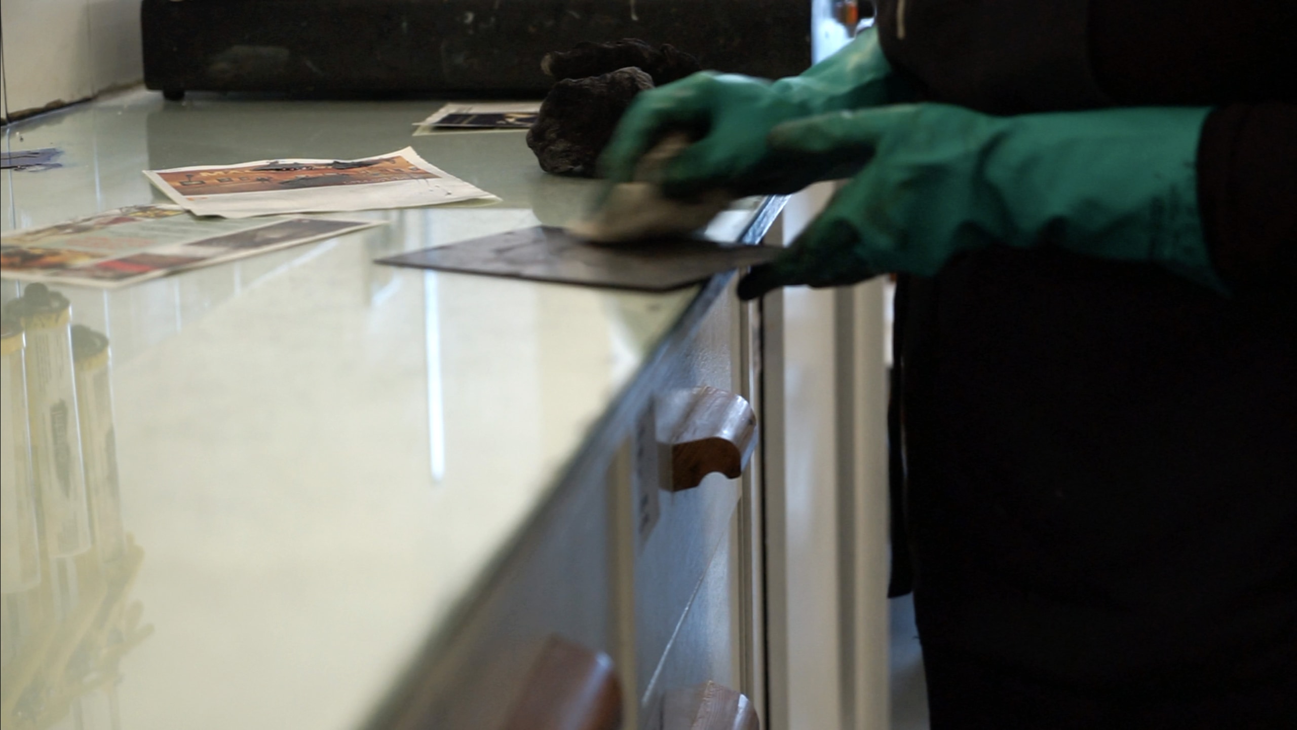 An Etching being handled by a person wearing rubber gauntlets