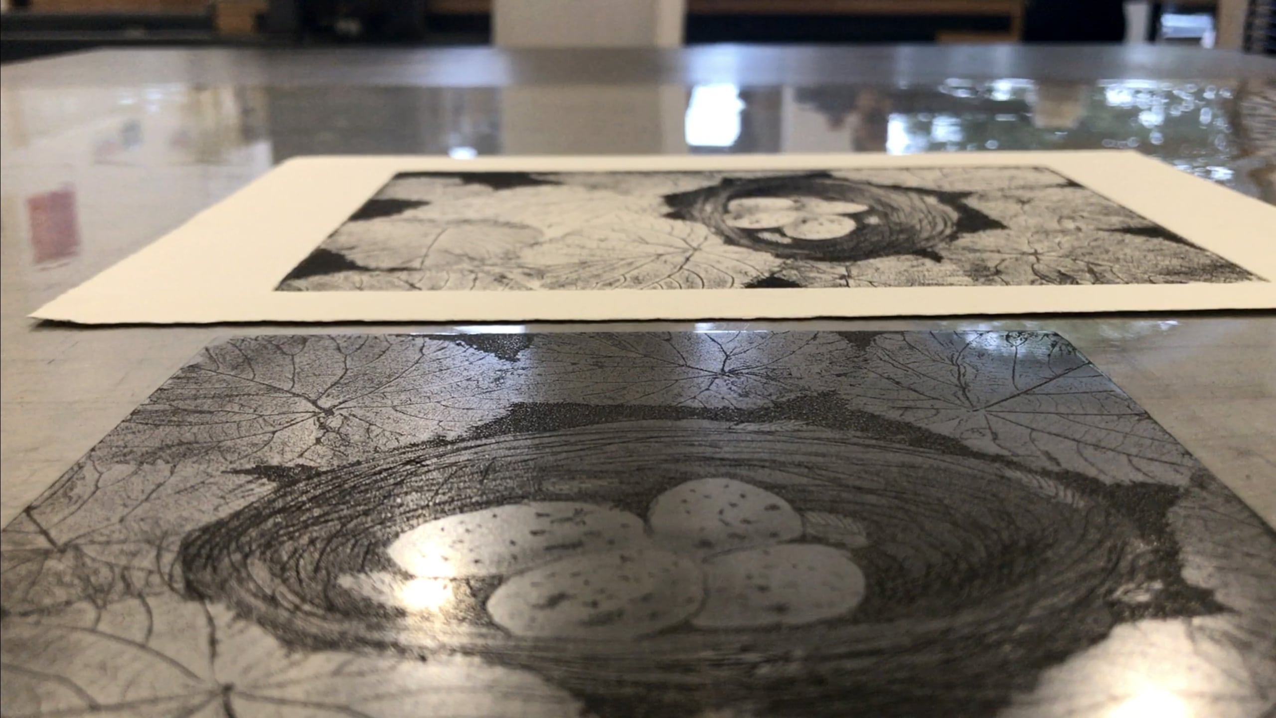 A finished stencil etching laying beside a print of the artwork it had made