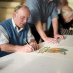 Elderly man signing his new artwork