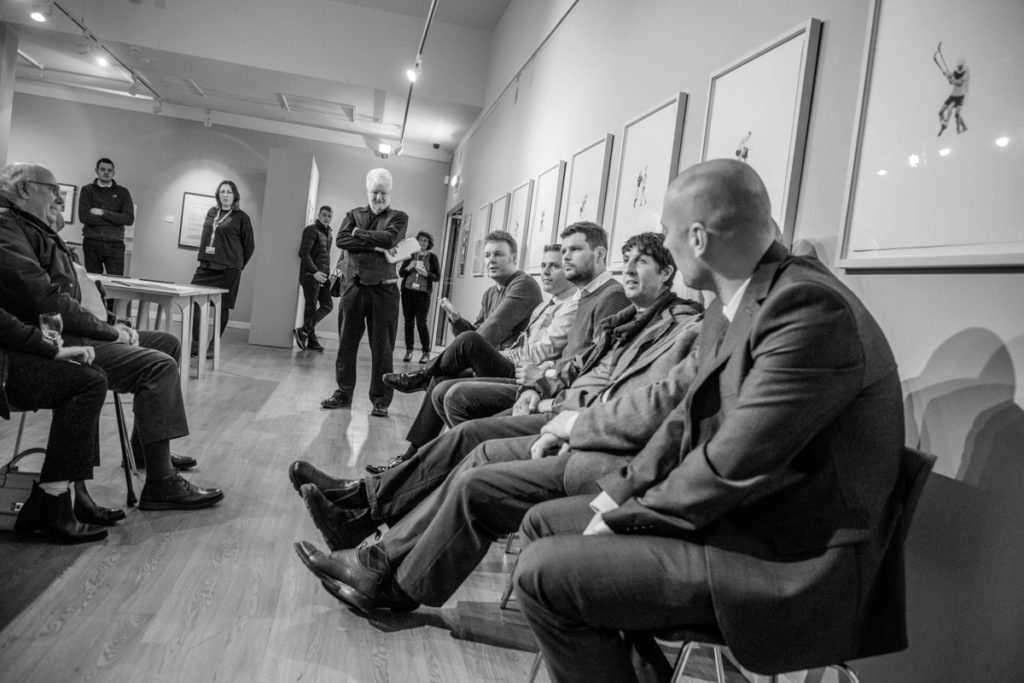 Group of people sitting down viewing artwork