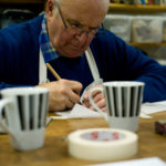 A person creating artwork with two cups in-front of them