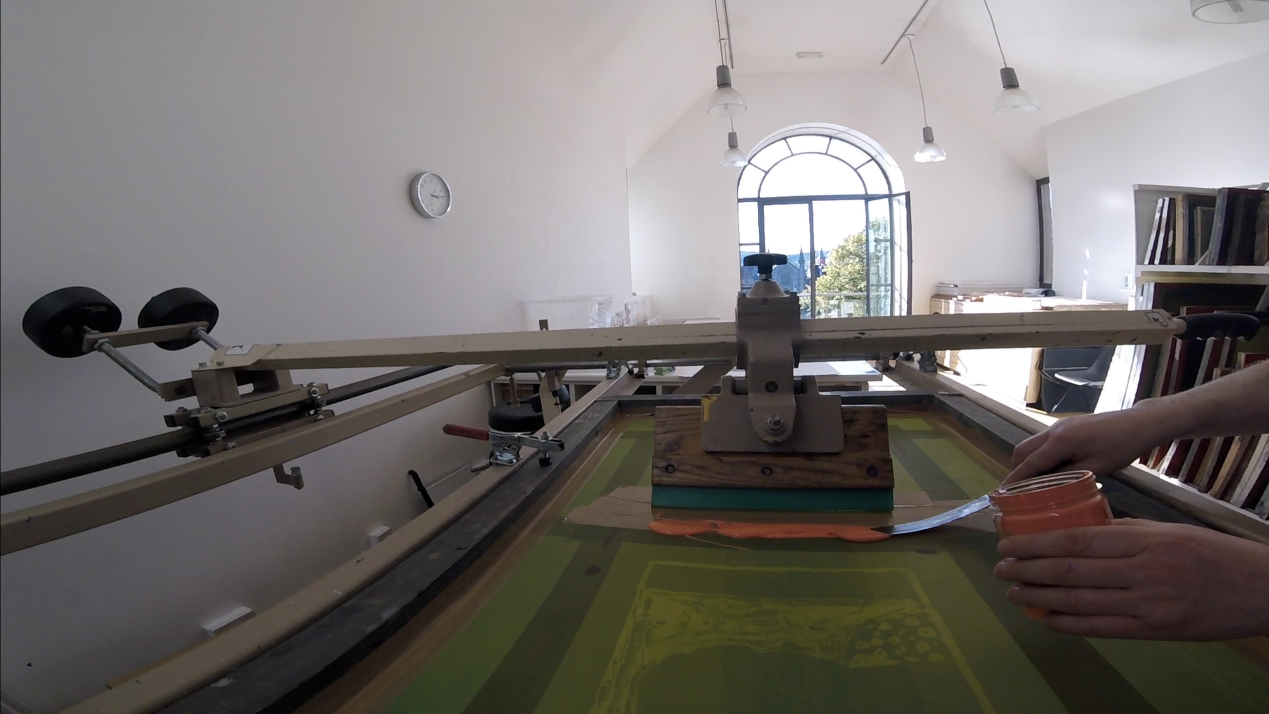 Screenprinting technique, a person has the stencil above the paper and uses a rubber squeegee to push the ink through onto the paper