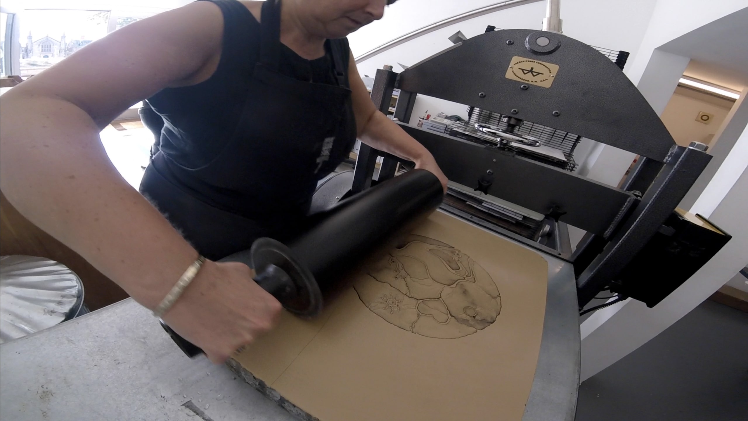 A person working on Stone Lithography be rolling ink over the stone