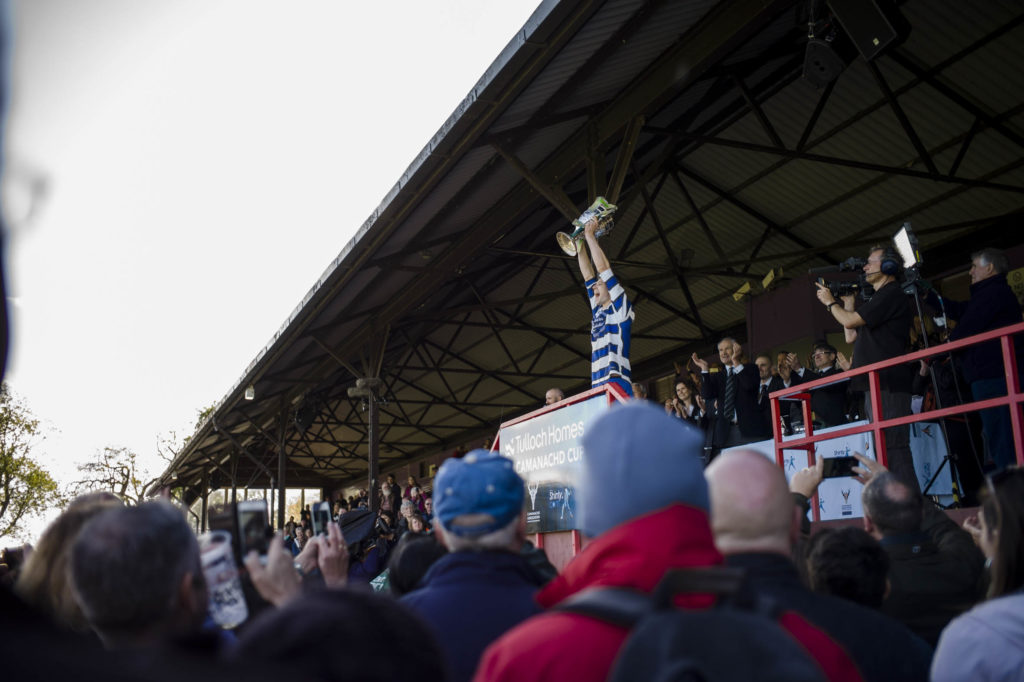 Crowd of people with a player lifting the cup